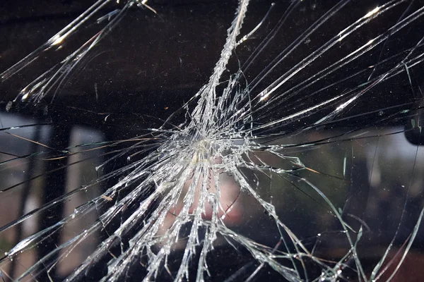 Cracks and glass shards radiate from the point of impact in a window that has been hit by an object