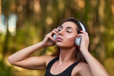 Genç bir kadın ormanda müzik dinliyor. Çalışırken müzik dinleyen bir kadın..