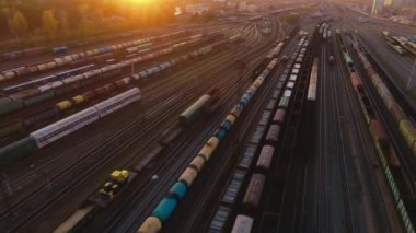 Helikopter gün batımında tren istasyonundan geçecek. Birçok vagon ve tren yolu bir endüstriyel yük istasyonunda. Ağır endüstri manzarası. Hava görünümü