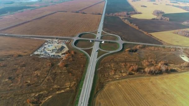 Vista aérea de una intersección de tráfico. Camiones y coches conducen por la carretera. Vista superior de la autopista en un día soleado. Autobahn. Logística de transporte. Campos hermosos 4K — Vídeos de Stock