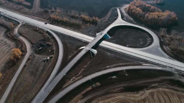 A drone takes off over a transport interchange under construction. Trucks and cars go along the highway. The road on a sunny day. Cargo transportation, logistics, cargo delivery. Transport logistics — Stock Video