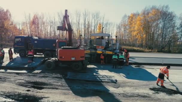 Novosibirsk Bölgesi, 2 Temmuz 2020. Novosibirskautor. Otoyolda inşaat işi. Kazı makinesinin işi. İşçi takımı asfaltı yerleştirdi. Bir dron yol ekipmanının yanında uçar. Ağır. — Stok video
