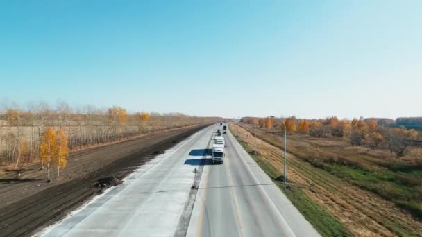 Bir İHA yol üzerinde uçuyor. Otoyol manzaralı ve araba kullanan bir otoban. Kargo taşımacılığı. Kamyonlar ve arabalar otoyol boyunca gider.. — Stok video