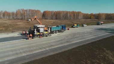 Novosibirsk Bölgesi, 2 Temmuz 2020. İşçiler yolu onarıyor. Özel makineli asfalt kaldırımlar ve işçiler beton karışımları hazırlıyorlar. Yolda inşaat işi var. Otoyol tamiri Yeni asfalt