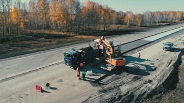 Novosibirsk Bölgesi, 2 Temmuz 2020. Novosibirskavtodor. Kazı makinesinin işi. Bir İHA yol ekipmanlarının etrafında uçuyor. Otoyolda inşaat işi. Ağır makineler. Kamyonlar yolda ilerliyor.