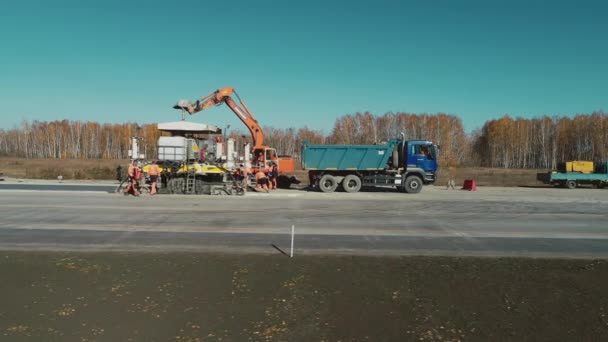 Gebiet Nowosibirsk, 2. Juli 2020. Nowosibirskawtodor. Arbeiter reparieren die Autobahn. Spezialausrüstung Fertiger. Arbeiter stapeln Betonmischungen. Straßenbau. Industrie — Stockvideo