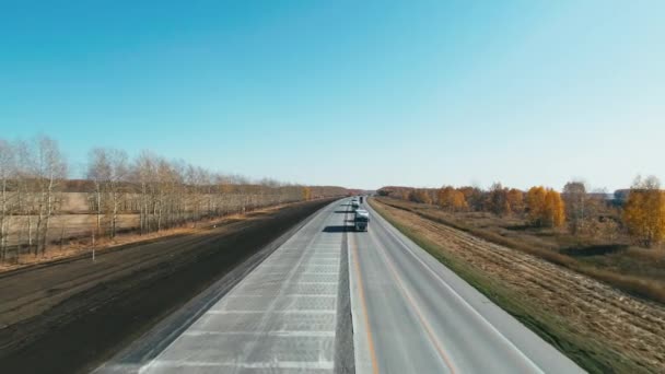 Bir İHA yol üzerinde uçuyor. Otoyol manzaralı ve araba kullanan bir otoban. Kargo taşımacılığı. Kamyonlar ve arabalar otoyol boyunca gider.. — Stok video