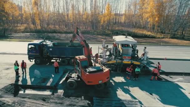 Obwód nowosybirski, 2 lipca 2020 r. Roboty budowlane na autostradzie. Prace koparki. Dron lata obok sprzętu drogowego. Ciężkie maszyny. Robota brukarza. Przemysł budowlany — Wideo stockowe