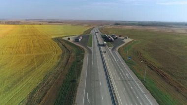 Kamyon otobanda park ediyor. Kargo taşımacılığı, lojistik, kargo teslimatı. Arabalar asfalt yolda gidiyor. Otoban 'da. Tarladan geçen yol..