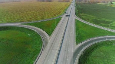 Bir İHA otoban boyunca uçuyor. Kamyonlar ve arabalar otoyol boyunca gidiyor. Güneşli bir günde yol. Otoban 'da. Kargo taşımacılığı, lojistik, kargo teslimatı. Güzel doğa.