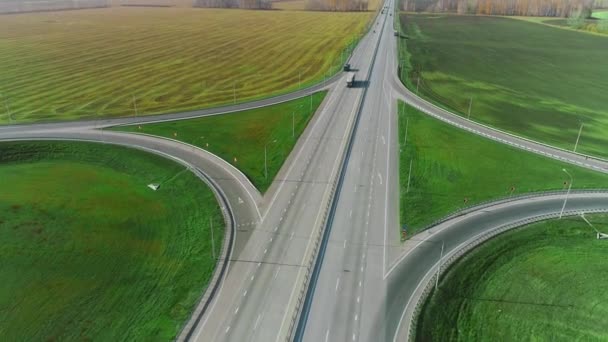 Podél dálnice letí dron. Náklaďáky a auta jedou po dálnici. Cesta za slunečného dne. Autobahn. Nákladní doprava, logistika, nákladní doprava. Krásná příroda — Stock video