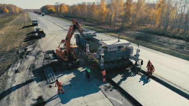 Novosibirsk Region, July 2, 2020. Construction work on the highway. The work of the excavator. A drone flies next to road equipment. Heavy machinery. Paver work. Construction industry — Stock Video