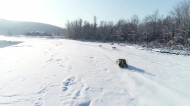 ATV 'ler karda yarışıyor. Hava görüntüsü: Dört tekerlekli bisiklette sürücü sürüşleri ve çapraz yarışta hovercraft. Kışın ekstrem spor. Güneşli bir gün, arka planda dağlar manzarası.