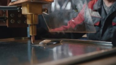 Koruyucu camın arkasında çalışan profesyonel bir işçi, metal işçiliği yapan bir makineyle çalışır. Zanaatkar, değirmenci ya da mühendis. Metal üretiminde yüksek lisans. Çalışırken kıvılcımlar uçuşuyor, yakın çekim.