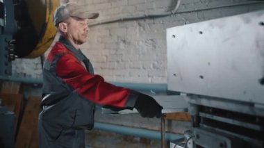 Profesyonel Kafkas mühendisi bir makine aletinde metal bir levha ile çalışır. Usta, çilingir üretimde. Metal işçiliği için makine aletleri. Fabrikada el işi ve otomatik çalışma..