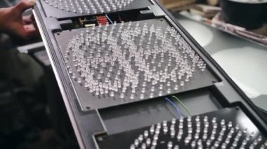 Bir işçi fabrikada yeni bir trafik lambasını tamir eder, test eder. LED 'ler, enerji tasarrufu trafik ışıkları, ampuller, elektronik.