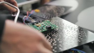 Bir işçi bir fabrikada trafik ışığı çipini bağlar. Yakın plan. LED 'ler, trafik lambaları, kablolar, elektronik aletler. Trafik ışıklarının onarımı ve montajı.
