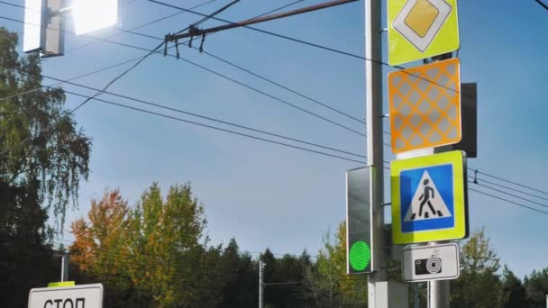 Close-up of traffic lights and road signs at an intersection in the city. Green traffic light. Urban road infrastructure. Blue sky — Stock Video