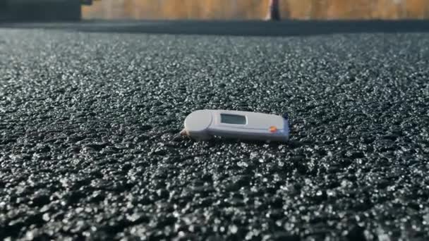 Pomiar temperatury świeżo ułożonego asfaltu. Zbliżenie dłoni człowieka wyciąga termometr do pomiaru temperatury asfaltu. Nowa nawierzchnia, roboty drogowe. Budowa nowej drogi. — Wideo stockowe