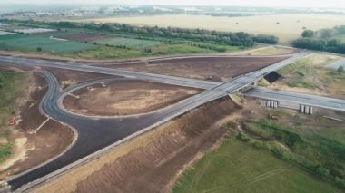 Trafik kavşağında uçuş. Otoyol kavşağı. Yol yapım aşamasında. Güzel manzara. Tarlalar ve ormanlar arasında otoyolun manzaralı bir manzarası. Şehir pisti. Yol