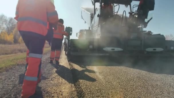 Novosibirská oblast, 3. srpna2020. Pracovník jde na čerstvý asfaltový povrch a měří jeho teplotu. Měření teploty čerstvého asfaltu. Digitální teploměr pro měření — Stock video