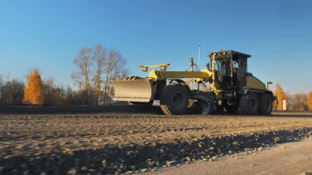 Um motonivelador nivela materiais de construção a granel para uma nova construção de estradas. Reparação da superfície da estrada. Máquinas de construção de estradas. Obras rodoviárias — Vídeo de Stock