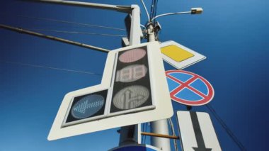 Mavi gökyüzü arka planına karşı yeni bir trafik ışığı ve yol işaretleri yakın plan. Kırmızı trafik ışığı.