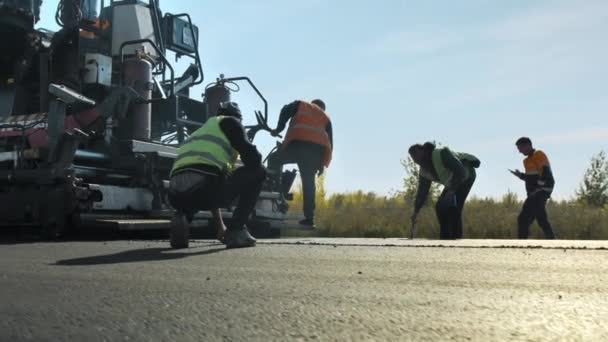 Región de Novosibirsk, 15 de agosto de 2020. Los trabajadores de la carretera toman medidas de un camino de asfalto recién puesto. Construcción de una nueva carretera. Reparación de carreteras. — Vídeo de stock