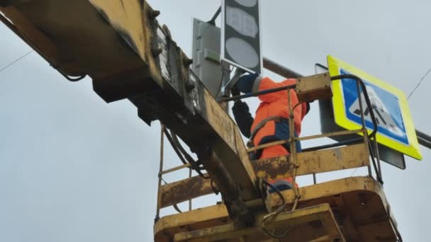 Um trabalhador em um berço de elevador repara um semáforo LED. Sinal de estrada. Tecnologia LED. Sinal de travessia para peões. — Vídeo de Stock