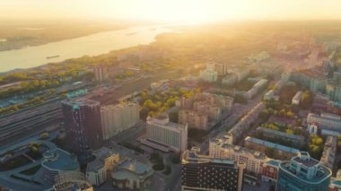 Nehirdeki büyük bir şehirde güzel bir günbatımının hava manzarası. Şehirdeki demiryolu rayları. Şehir hayatı. Altın saat