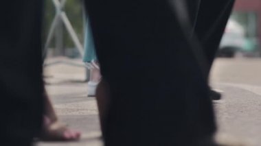 Bir yaya kalabalığı yoldan geçen arabaların arka planına karşı karşıya geliyor. Kalabalık bir yaya geçidi trafiği vardı. Koşan insanların bacaklarına yakın çekim. Şehir hayatı. Yavaş çekim