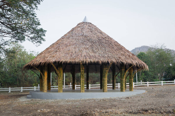 Building with straw roof on green trees background
