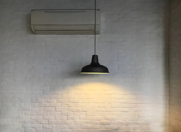 Black fixture of lamp hanging on ceiling and have white bricks wall is background for interior decoration design.