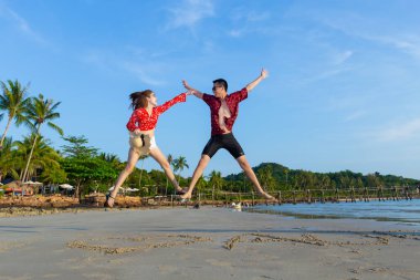 Genç aşık çift sahilde atlama.