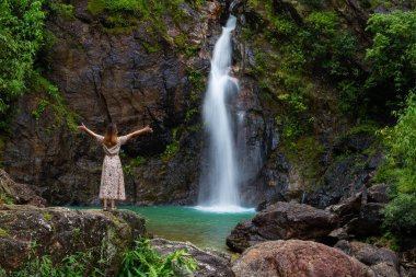 Tayland 'ın kayalık dağındaki şelalede duran turist kadın..
