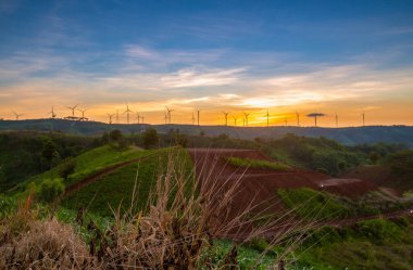 Siluet rüzgar türbini alacakaranlık gökyüzü ve güneş ışığı dağdaki temiz enerji santrali için..