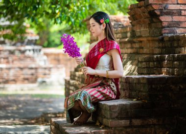 Güzel Taylandlı bir kadın elinde kırmızı şemsiyeyle koridorda yürürken Tayland 'ın başkenti Ayutthaya' da eski bir tapınakta Tayland geleneğiyle meditasyon yapıyor..