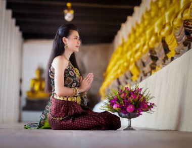 Taylandlı güzel bir kadın, Tayland 'ın Ayutthaya ilinde eski bir tapınakta Buda için dua edecek pembe nilüferleri var.. 