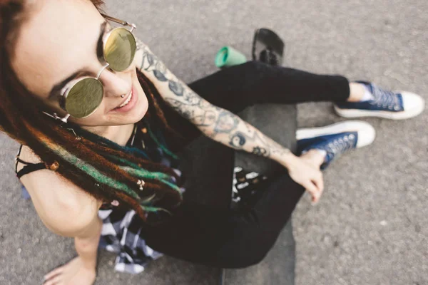 Chica joven con tatuaje y rastas sentado en el parque — Foto de Stock