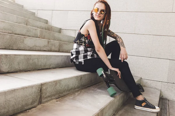 Chica joven con tatuaje y rastas sentado en las escaleras —  Fotos de Stock