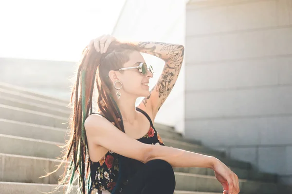 Chica joven con tatuaje y rastas sentado en las escaleras — Foto de Stock