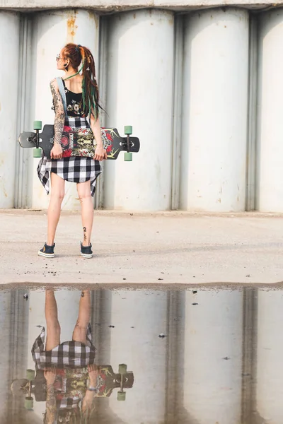 UFA, RUSIA - 12 de septiembre de 2018 Foto editorial de una joven con un longboard sobre el fondo de una estructura de hormigón —  Fotos de Stock