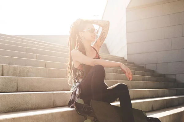 Chica joven con tatuaje y rastas sentado en las escaleras — Foto de Stock