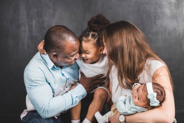 Siyah duvar arka plan üzerinde iki çocuklu uluslararası bir aile portresi