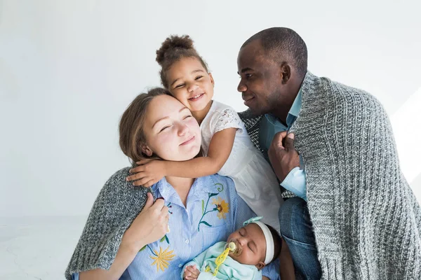El padre amoroso cubre a su familia con una manta a cuadros. Feliz familia multiétnica. Valores familiares — Foto de Stock