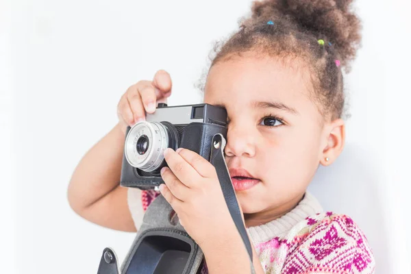 Retrato de una niña pequeña en un vestido colorido tomando fotos en una vieja cámara vintage — Foto de Stock