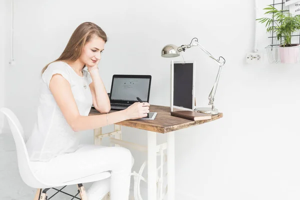 Young business woman working at home and draws on the tablet. Creative Scandinavian style workspace