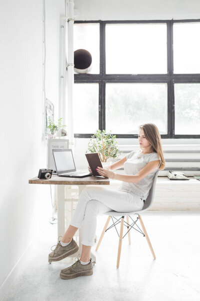 Young business woman working at home and reading a book. Creative Scandinavian style workspace