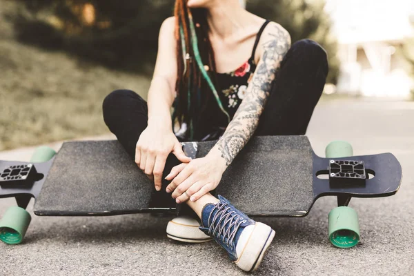 Chica joven con tatuaje y rastas sentado en el parque —  Fotos de Stock