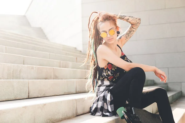 Chica joven con tatuaje y rastas sentado en las escaleras —  Fotos de Stock